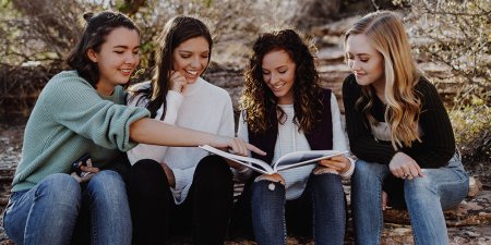 Happy students gathered around a yearbook.