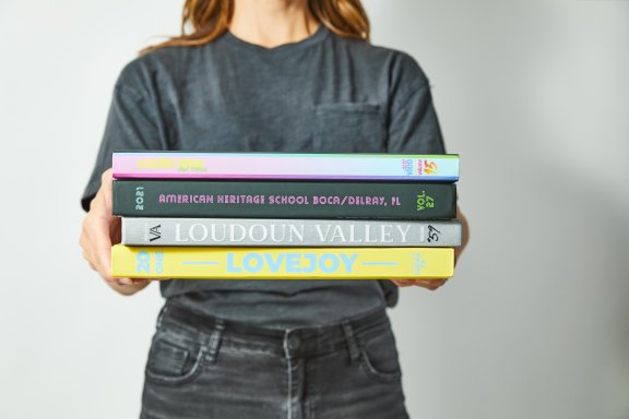 Student holding four different yearbooks.